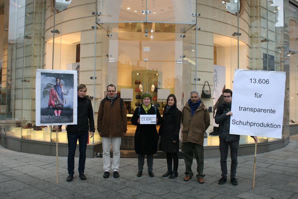 Mitarbeiter der Clean Clothes Kampagne mit Unterschriftenliste vor einem Schuhgeschäft
